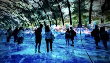 A group of people standing around watching the Blue Paradox immersive experience. 