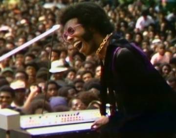 Sly Stone singing and playing the keyboard at the Harlem Cultural Festival in New York City. 